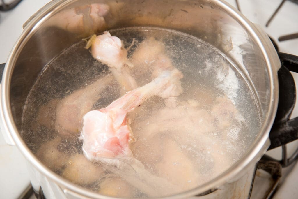 chicken bones simmering in a pot to make chicken bone broth 