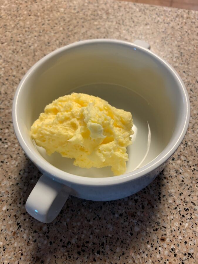 A cup with raw Jersey milk cow butter made from churning butter in a glass jar. 