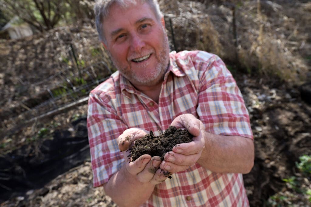 A man holds healthy soil in his hands that he got from his garden where he avoided using a garden till. 