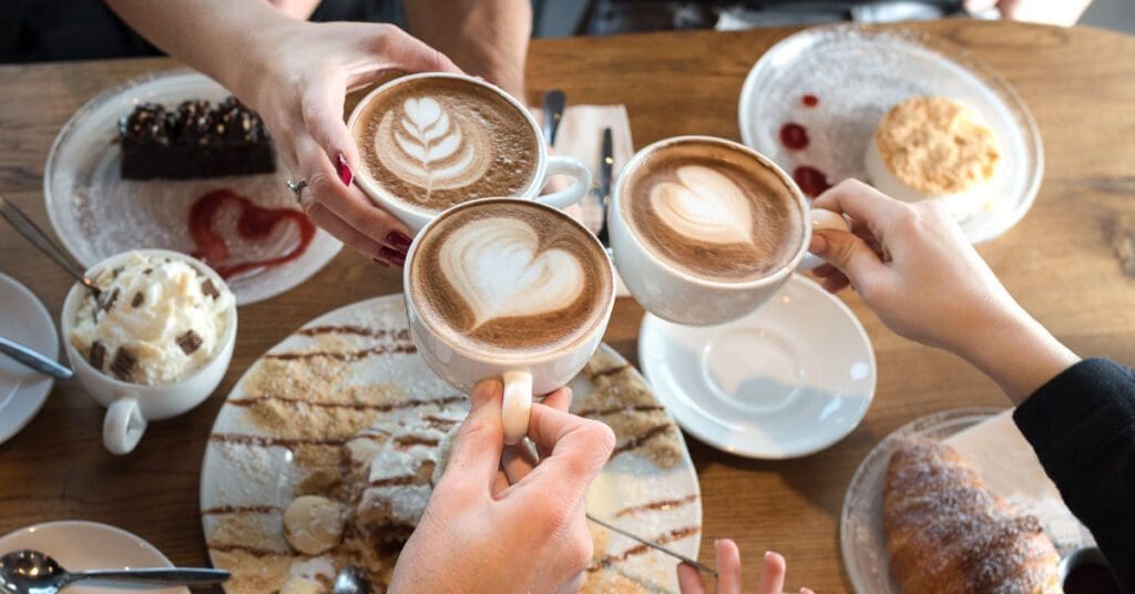 A group of people are toasting with their cups of coffee over dessert as part of an Easter feast. 