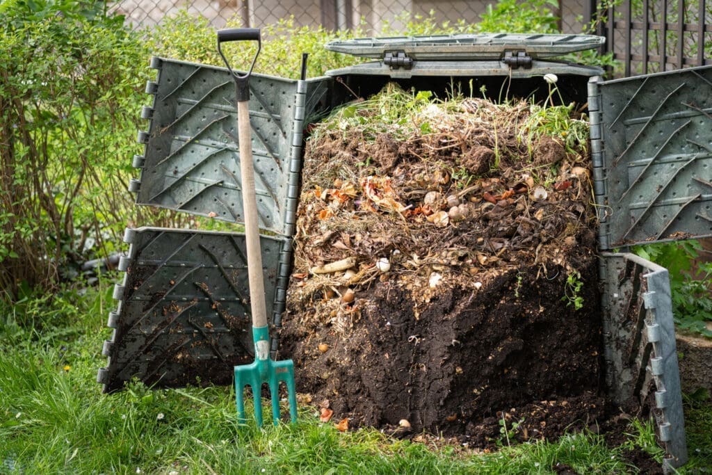 The doors are open on a  full compost bin, revealing the bottom layer of material is finished composting and ready for removal. 