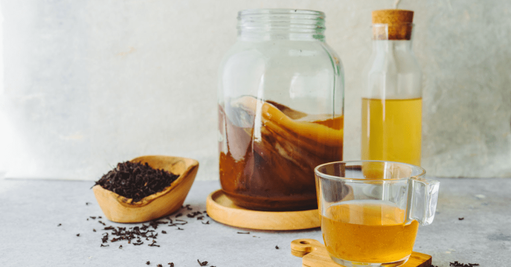 Homemade kombucha recipes use three ingredients pictured here: tea bags, sugar, and SCOBY. The ingrients sit in glass jars for fermenting. 